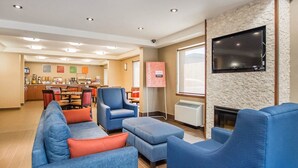 A hotel lobby with a seating area, a kitchen, and a fireplace. - Comfort Inn (Bathurst)