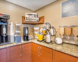 A hotel kitchen with a coffee maker, microwave, and breakfast bar.