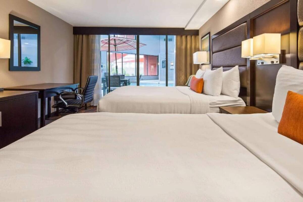 A hotel room with two beds, a desk, and a chair.