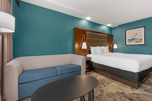 A hotel room with a bed, a sofa, a small table, and a painting on the wall. - The Great Rivers, an Ascend Collection Hotel (Alton)