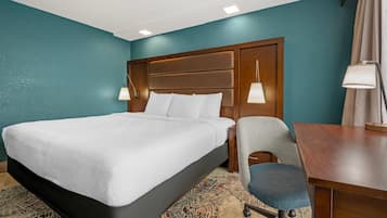 Ein Hotelzimmer mit einem großen Bett, einem Schreibtisch, einem Sessel und zwei Nachttischlampen.