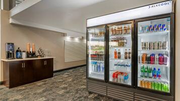 Un hall de hotel con minibar, refrigerador lleno de bebidas y estación de café.