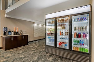 Un hall de hotel con minibar, refrigerador lleno de bebidas y estación de café.