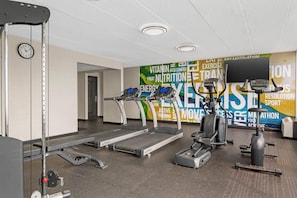 Et fitnessrum med løbebånd, spinningcykler og styrketræningsudstyr.