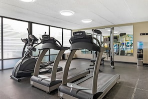 A gym with treadmills, exercise equipment, and a water dispenser.