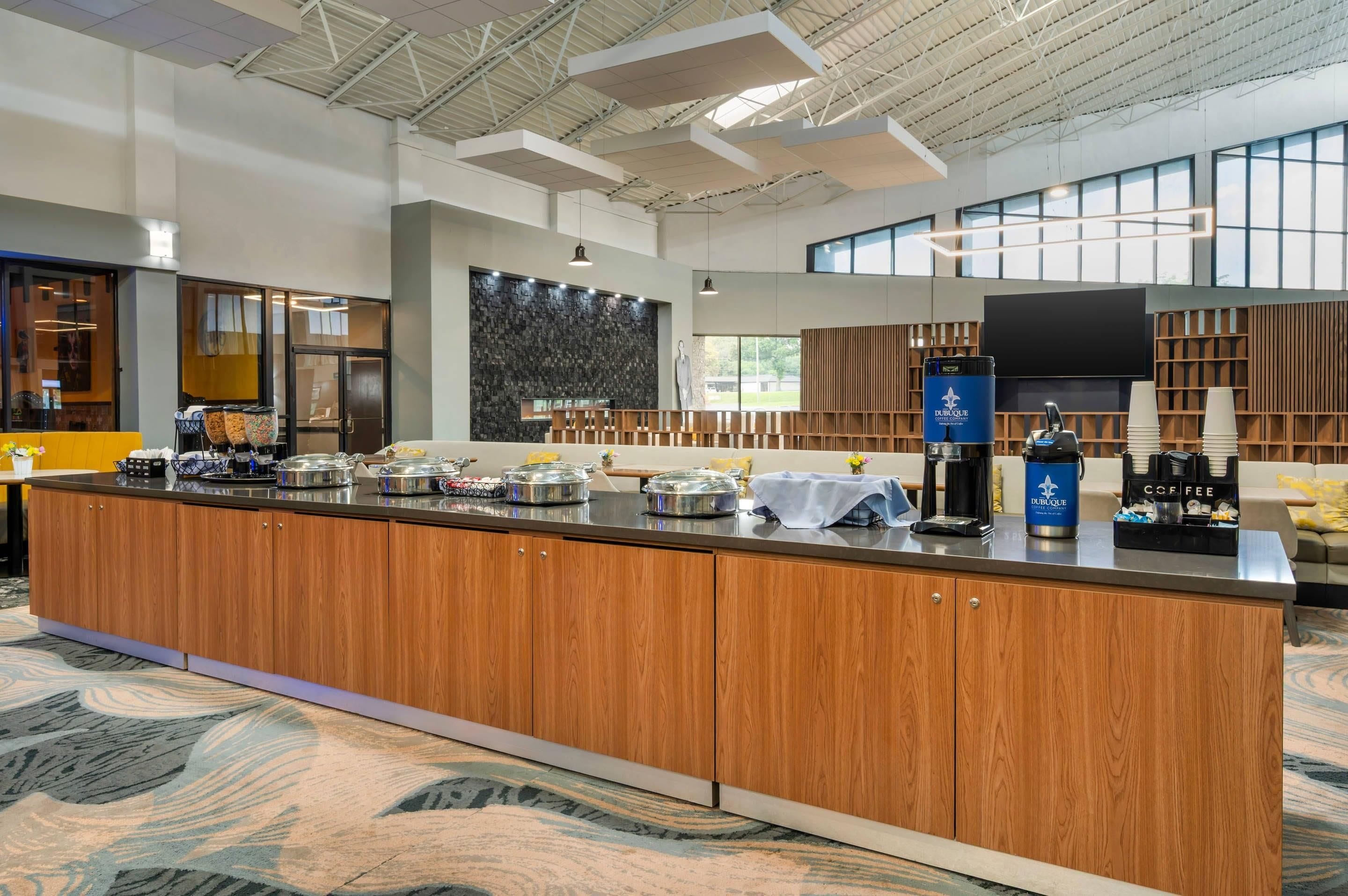 A modern kitchen area with a central island, coffee machines, and a large window providing natural light.