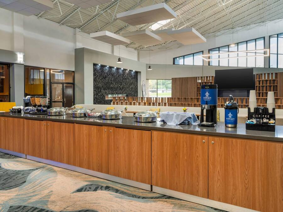 A modern kitchen area with a central island, coffee machines, and a large window providing natural light.