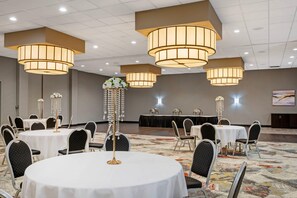 A conference room with round tables, chairs, and chandeliers.