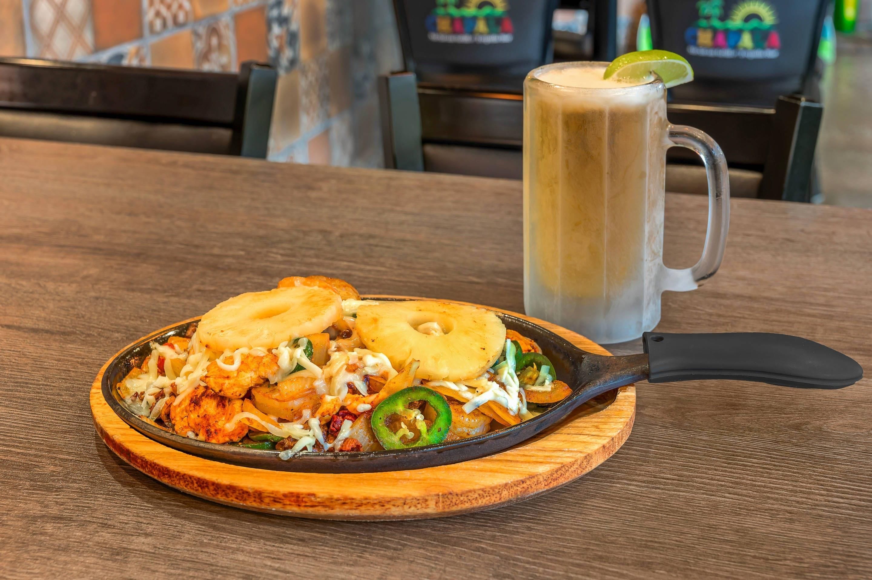 A meal with a skillet, a mug, and a lime wedge on a wooden table.