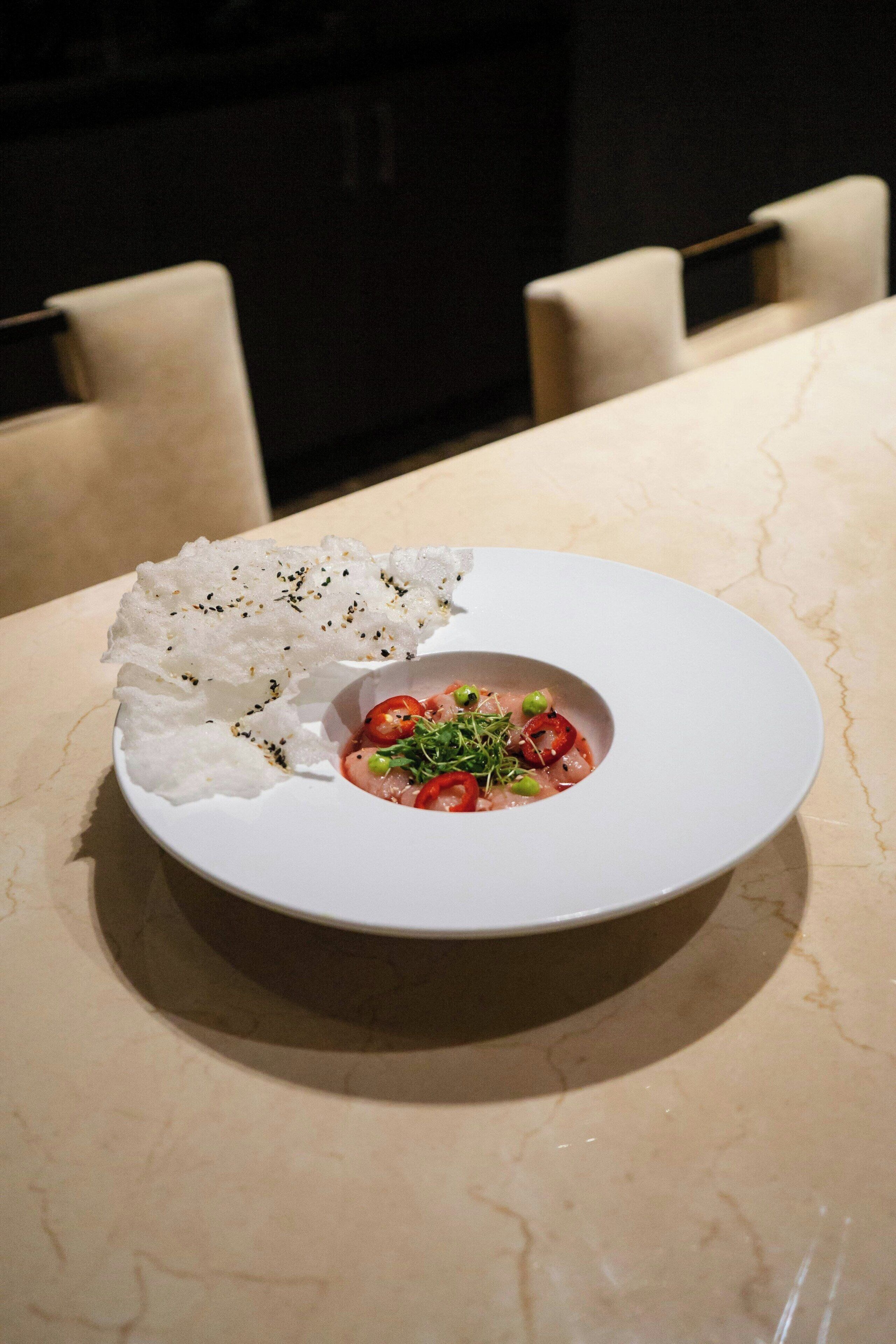 A white plate with a dish of food on a marble table.