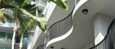 A modern multi-story building with balconies, a well-maintained garden, and outdoor seating.