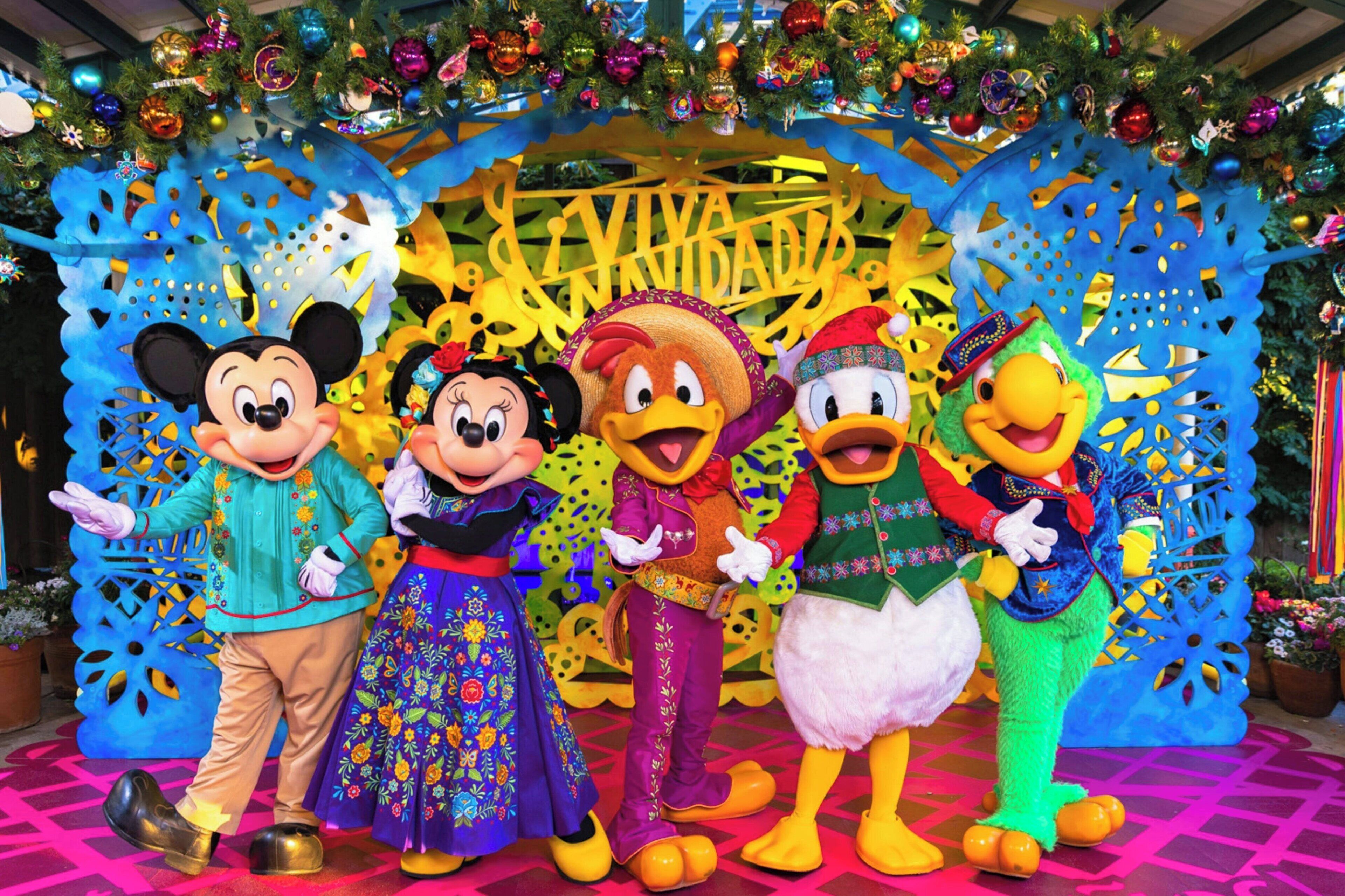 A group of animated characters in front of a festive backdrop with a sign that reads "VIVA UNIDAD".