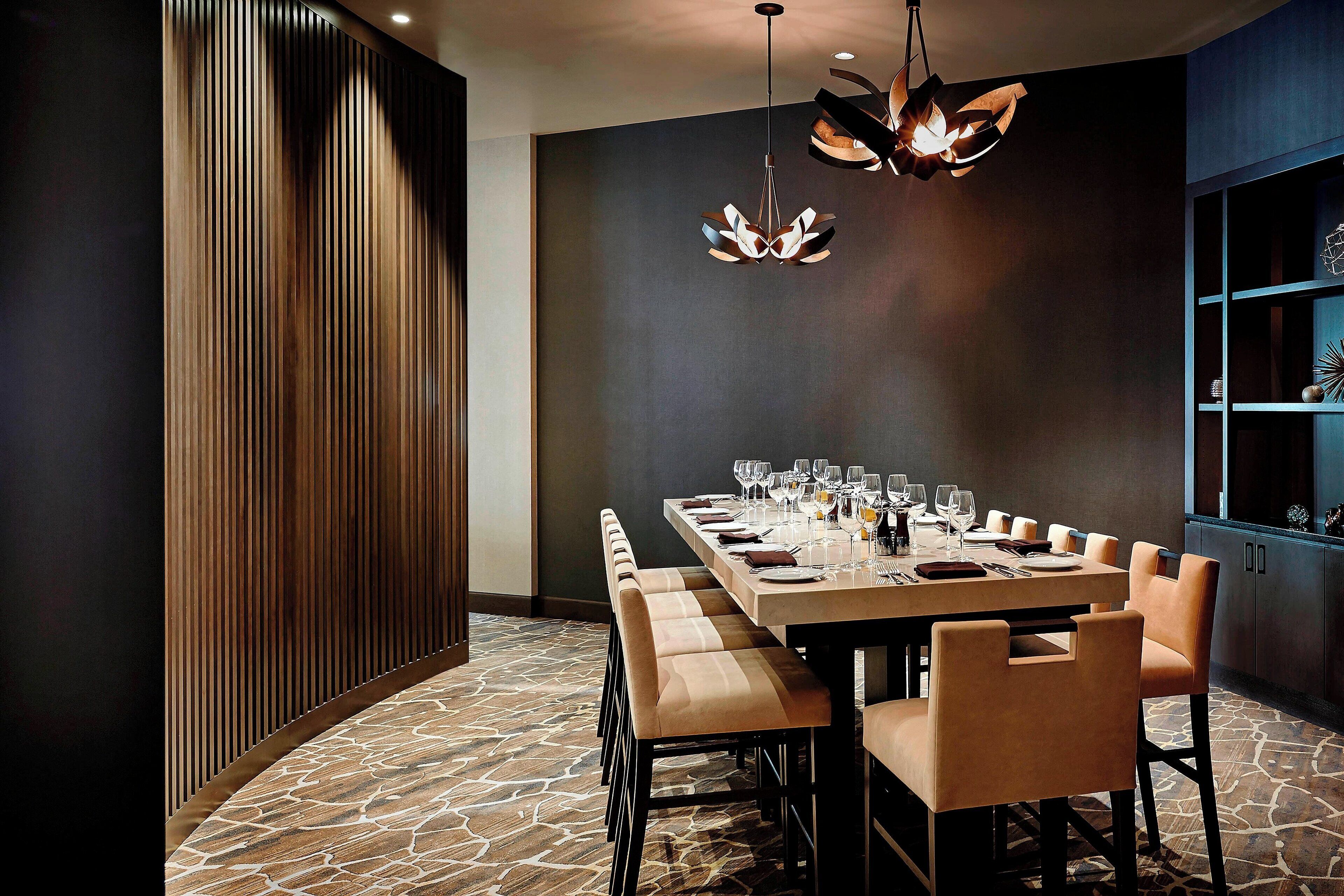 Un comedor moderno con una mesa larga dispuesta para seis comensales, paneles de madera en una pared y un suelo con diseño de piedra.