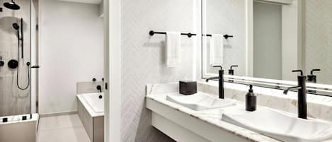 A modern bathroom with two sinks, a large mirror, and a shower area.