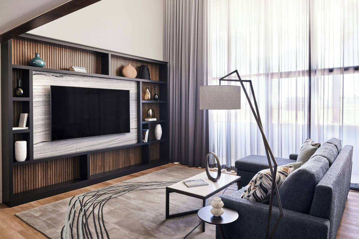 A modern living room with a large flat-screen TV, a sofa, a coffee table, and a floor lamp.