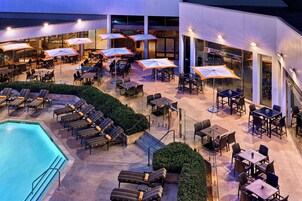 Una piscina al aire libre, sombrillas, sillones reclinables de piscina