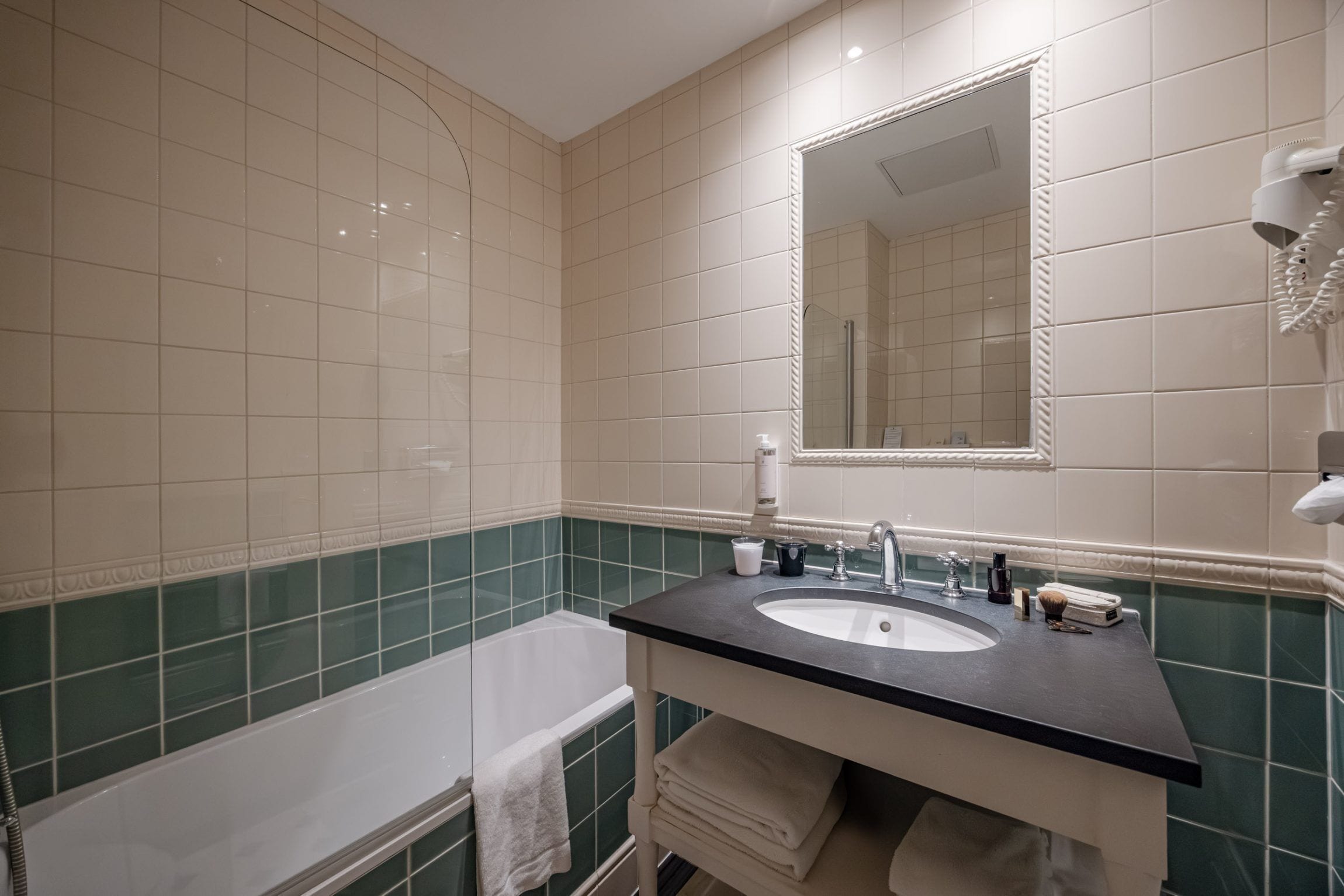 Une salle de bain avec une baignoire, un lavabo, un miroir et un porte-serviettes.