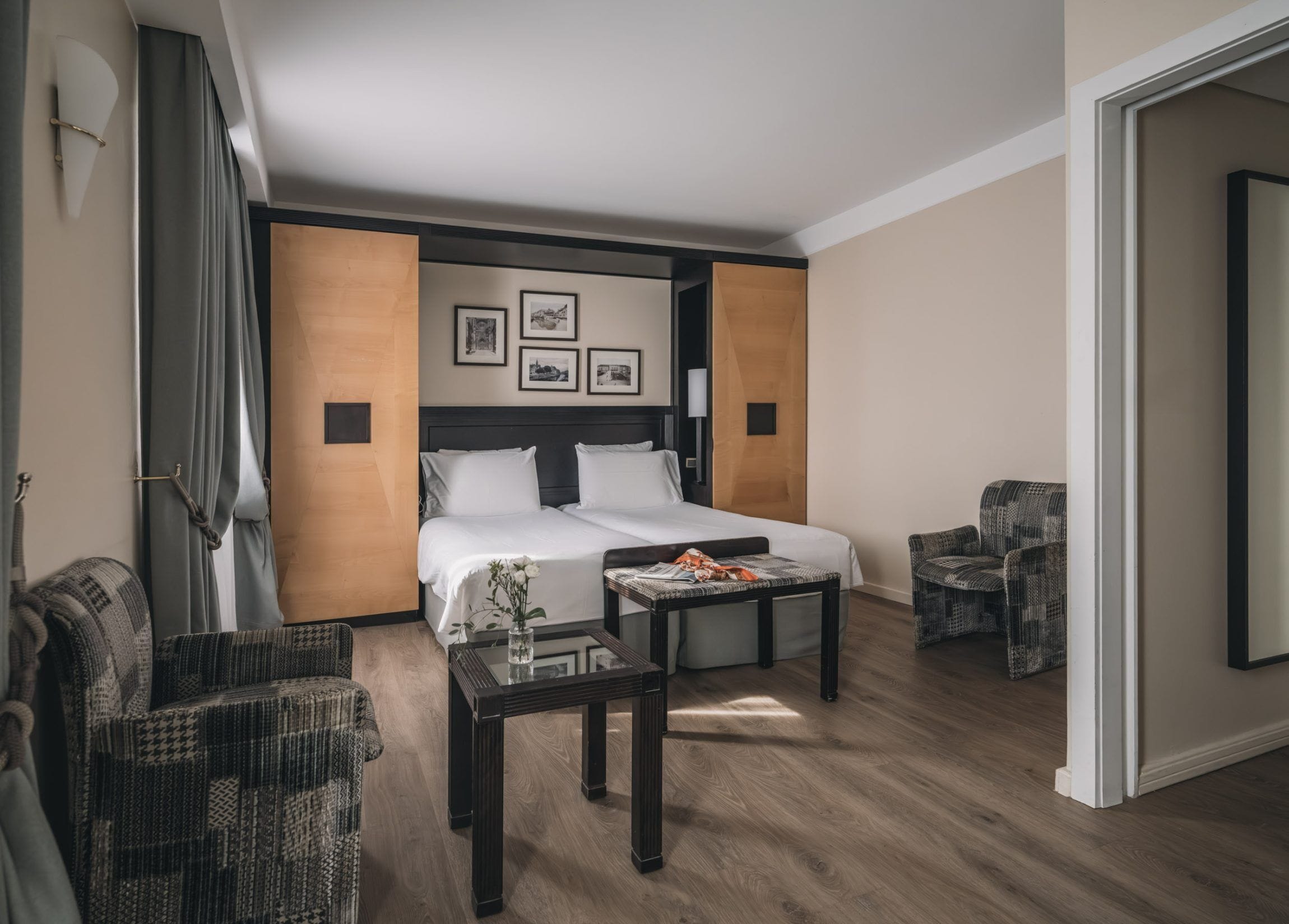 A hotel room with a bed, a small table, two chairs, and a mirror.