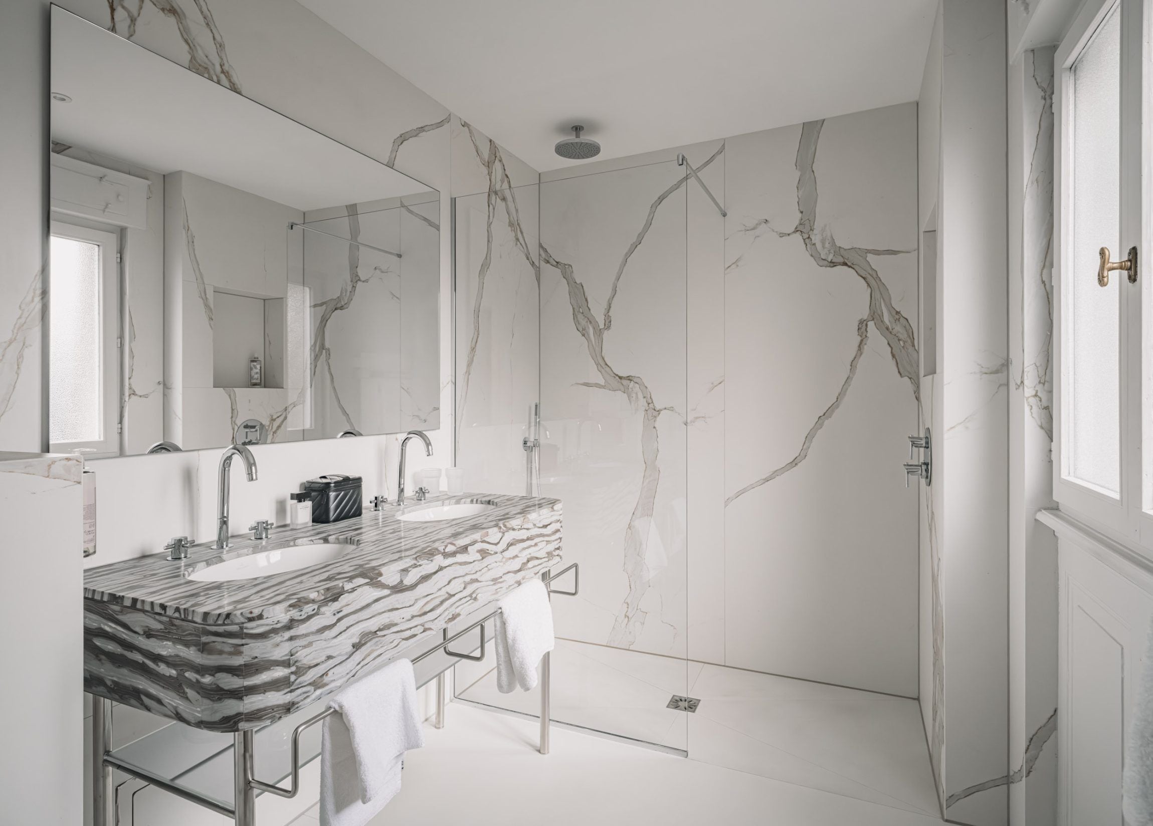 Une salle de bain avec deux lavabos, un grand miroir et une douche.