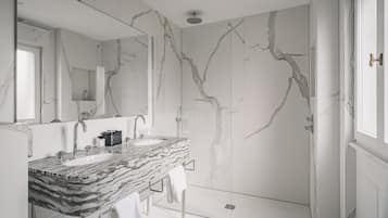 Une salle de bain avec deux lavabos, un grand miroir et une douche.