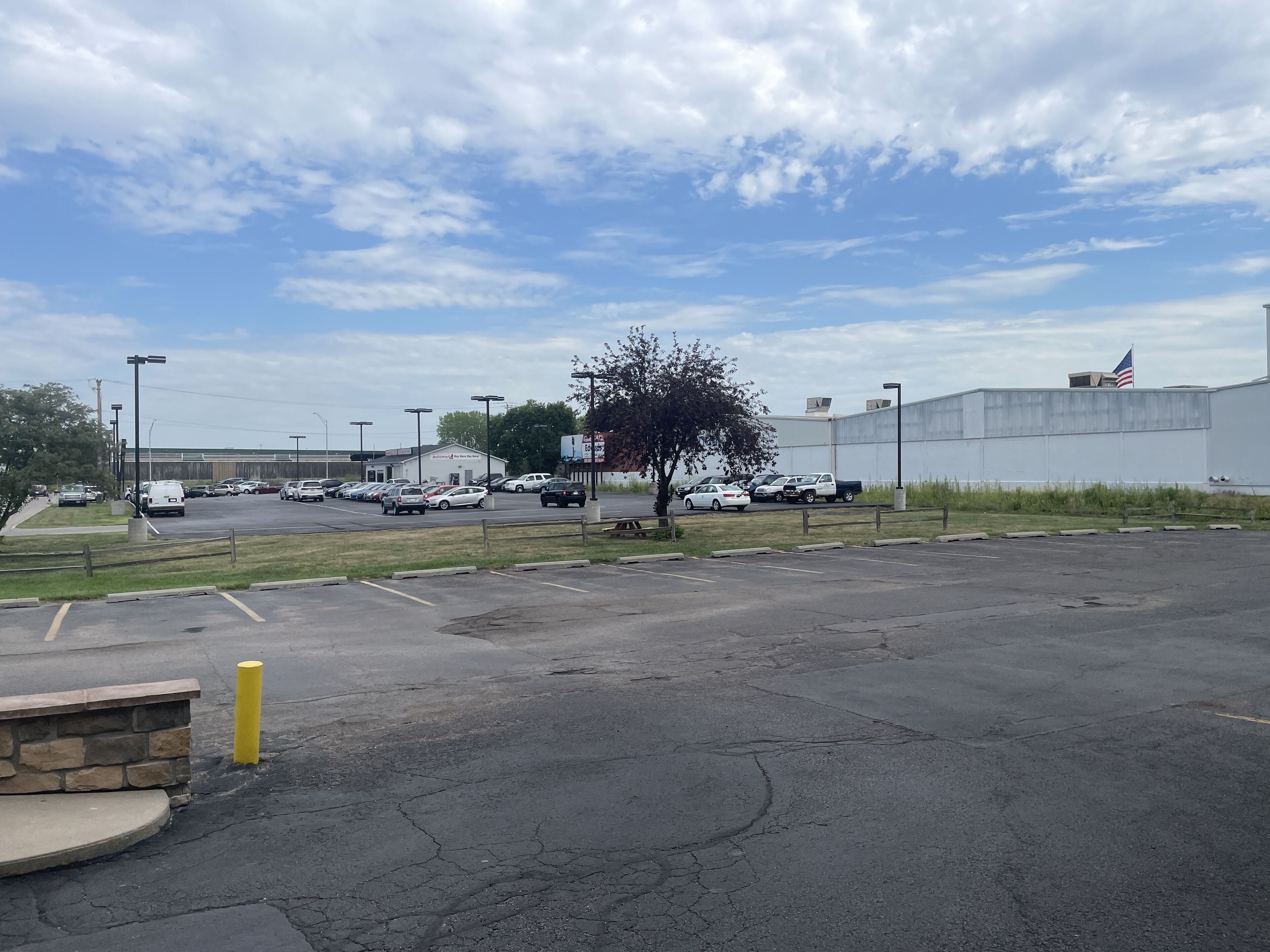 A parking lot with several cars, a building with a sign, and a flag.