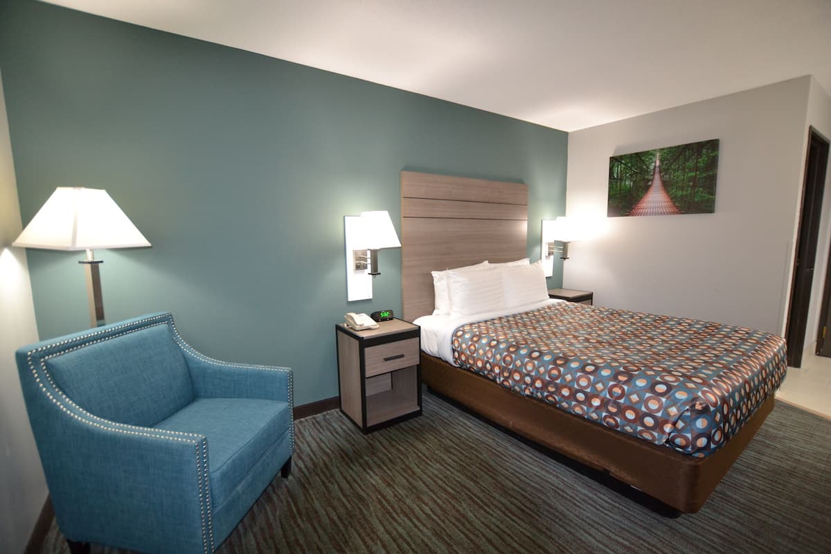 Ein Hotelzimmer mit Bett, Stuhl, Nachttisch und Lampe.