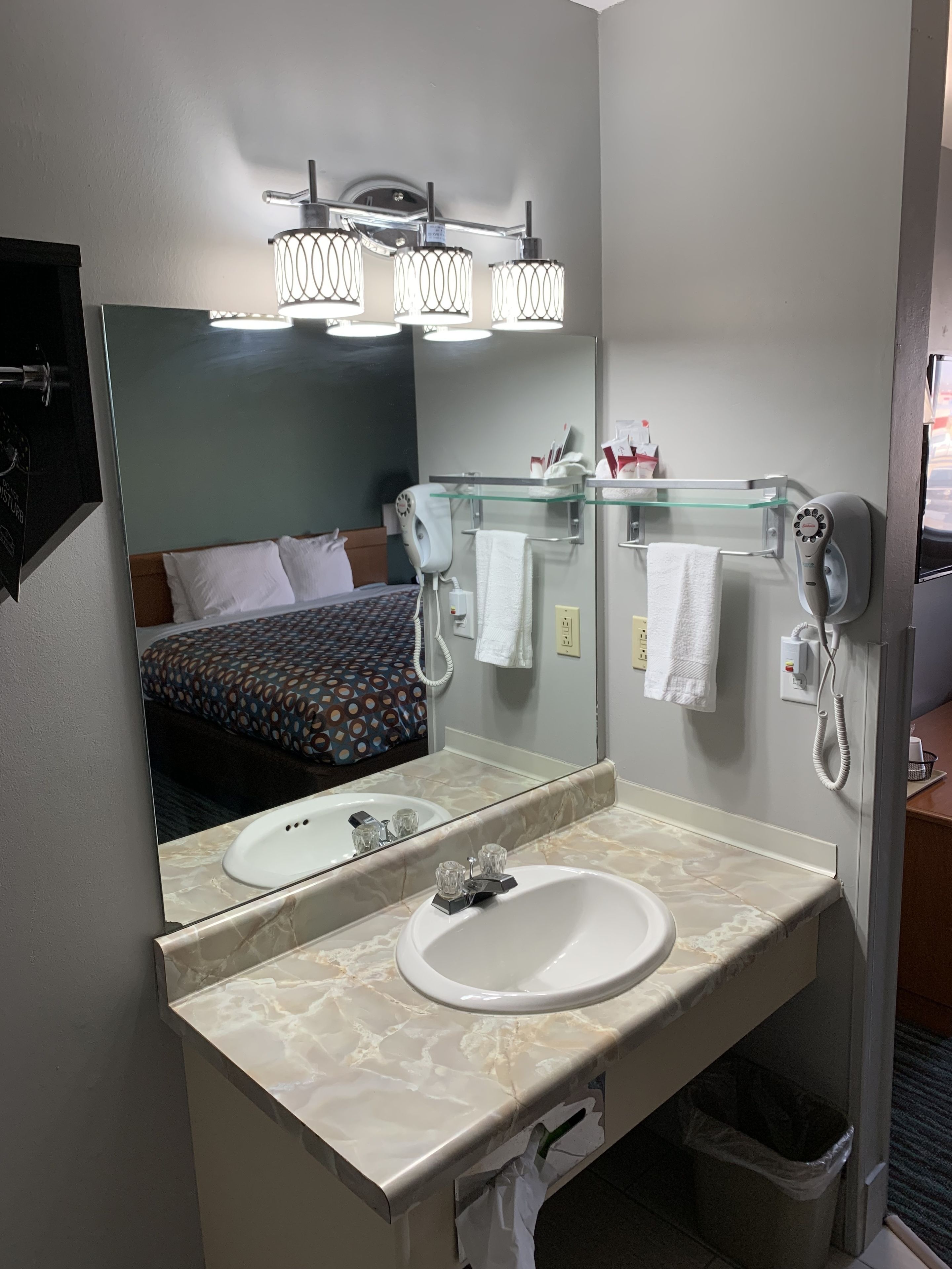 Un baño de hotel con lavamanos de mármol, un espejo grande, un secador de pelo y un toallero.