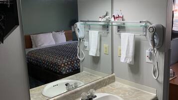 Un baño de hotel con lavamanos de mármol, un espejo grande, un secador de pelo y un toallero.