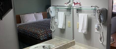 Un baño de hotel con lavamanos de mármol, un espejo grande, un secador de pelo y un toallero.