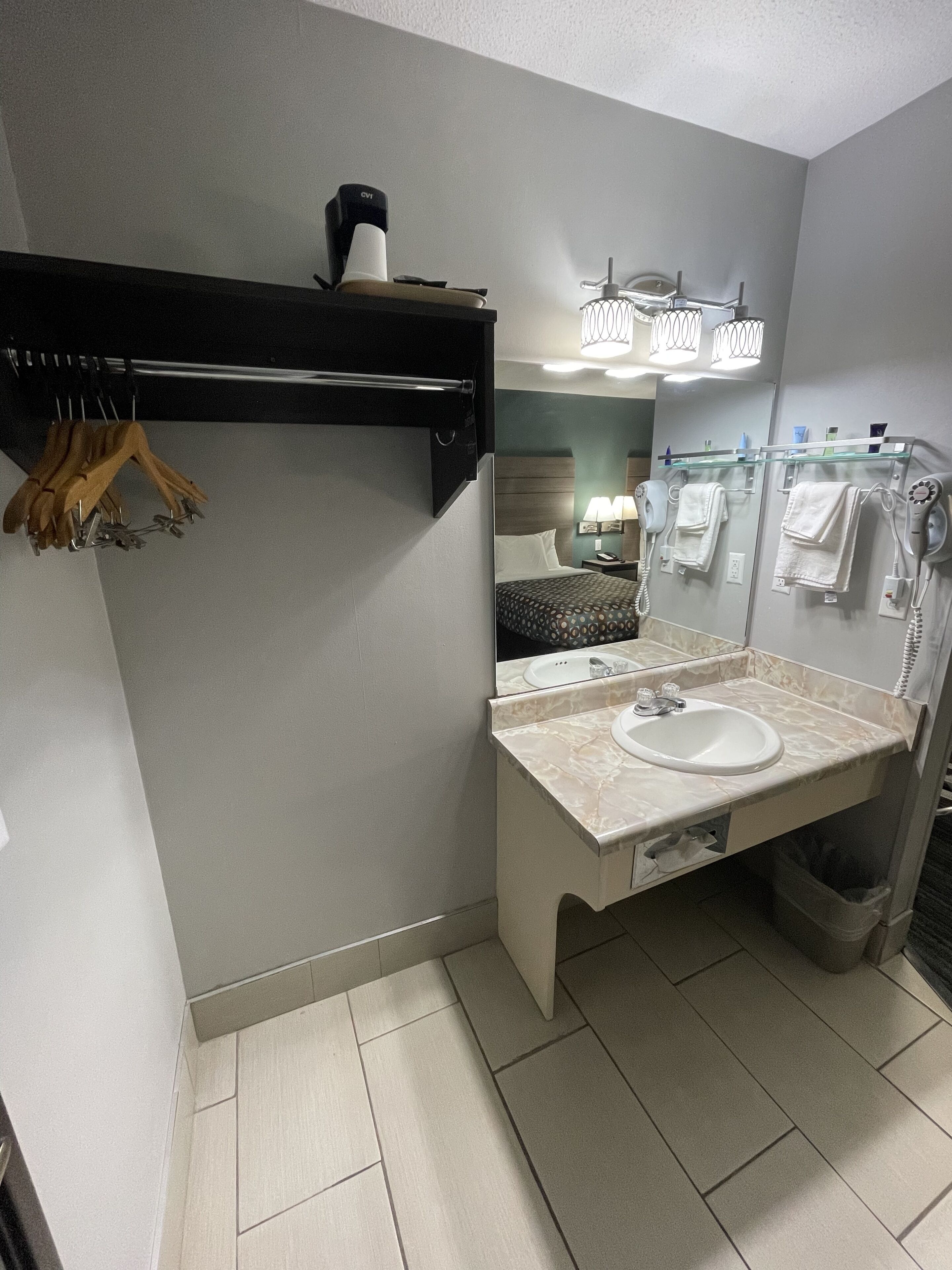 Un baño moderno con un lavabo blanco, un perchero para toallas, un secador de pelo y un espejo.