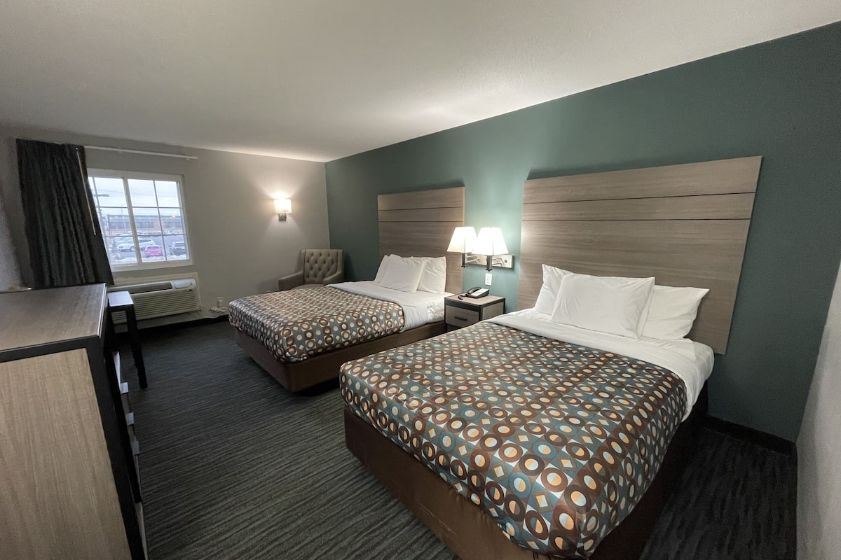 Ein Hotelzimmer mit zwei Betten, einem Schreibtisch und einem Fenster.