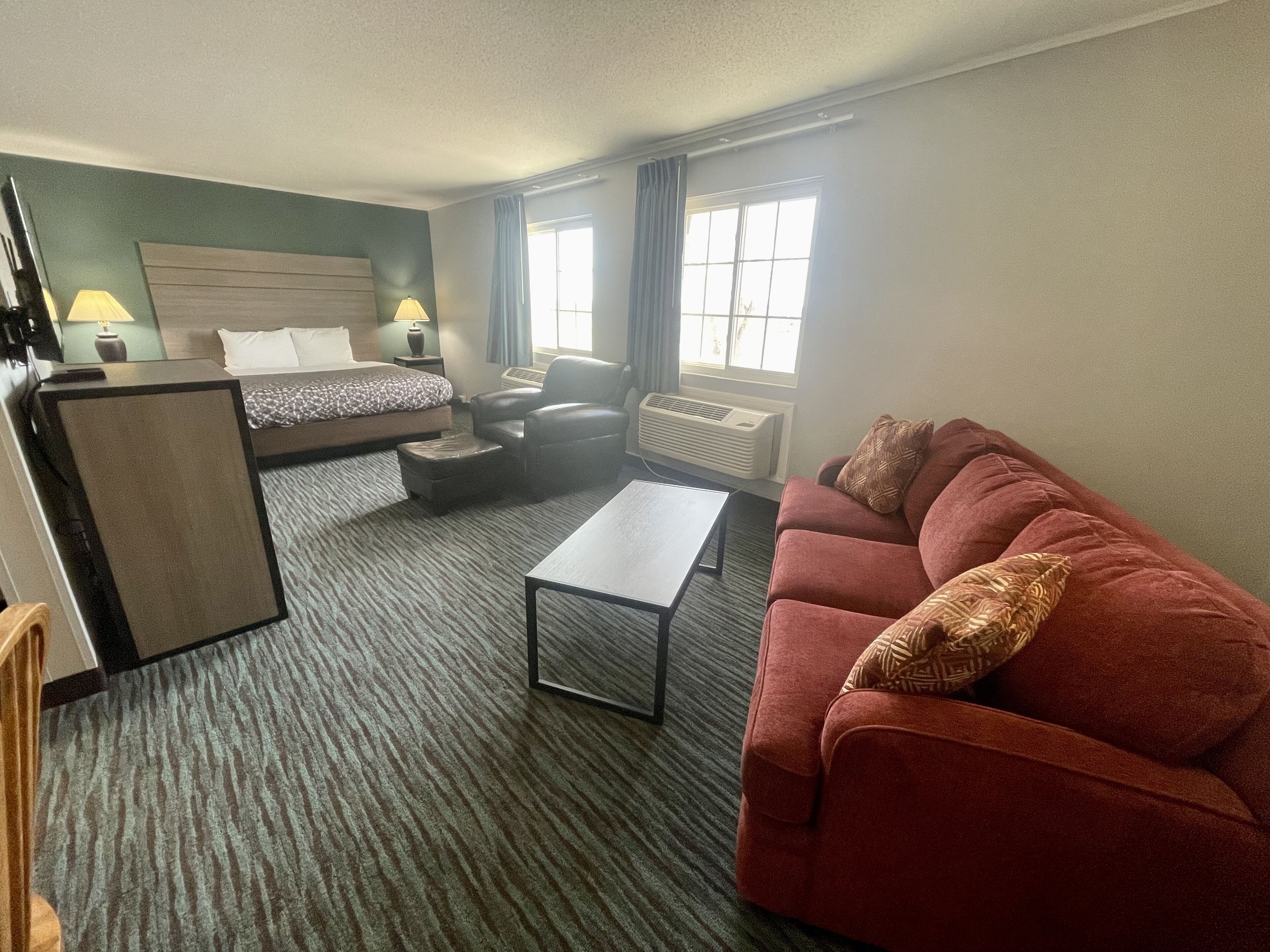 A hotel room with a bed, a sofa, a desk, and a chair.