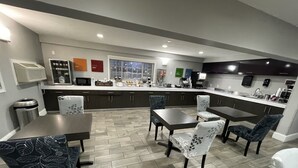 A modern kitchen with dark cabinets, a white countertop, and a dining area with patterned chairs.