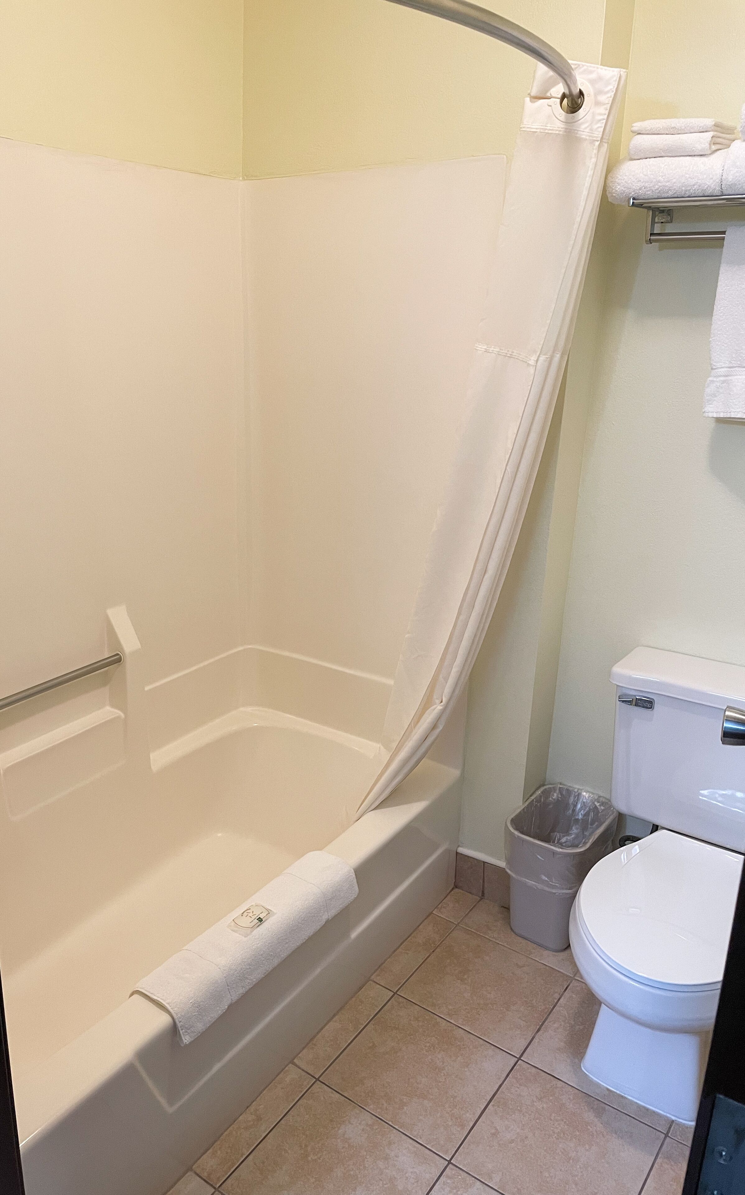 A bathroom with a bathtub, toilet, and a trash can.