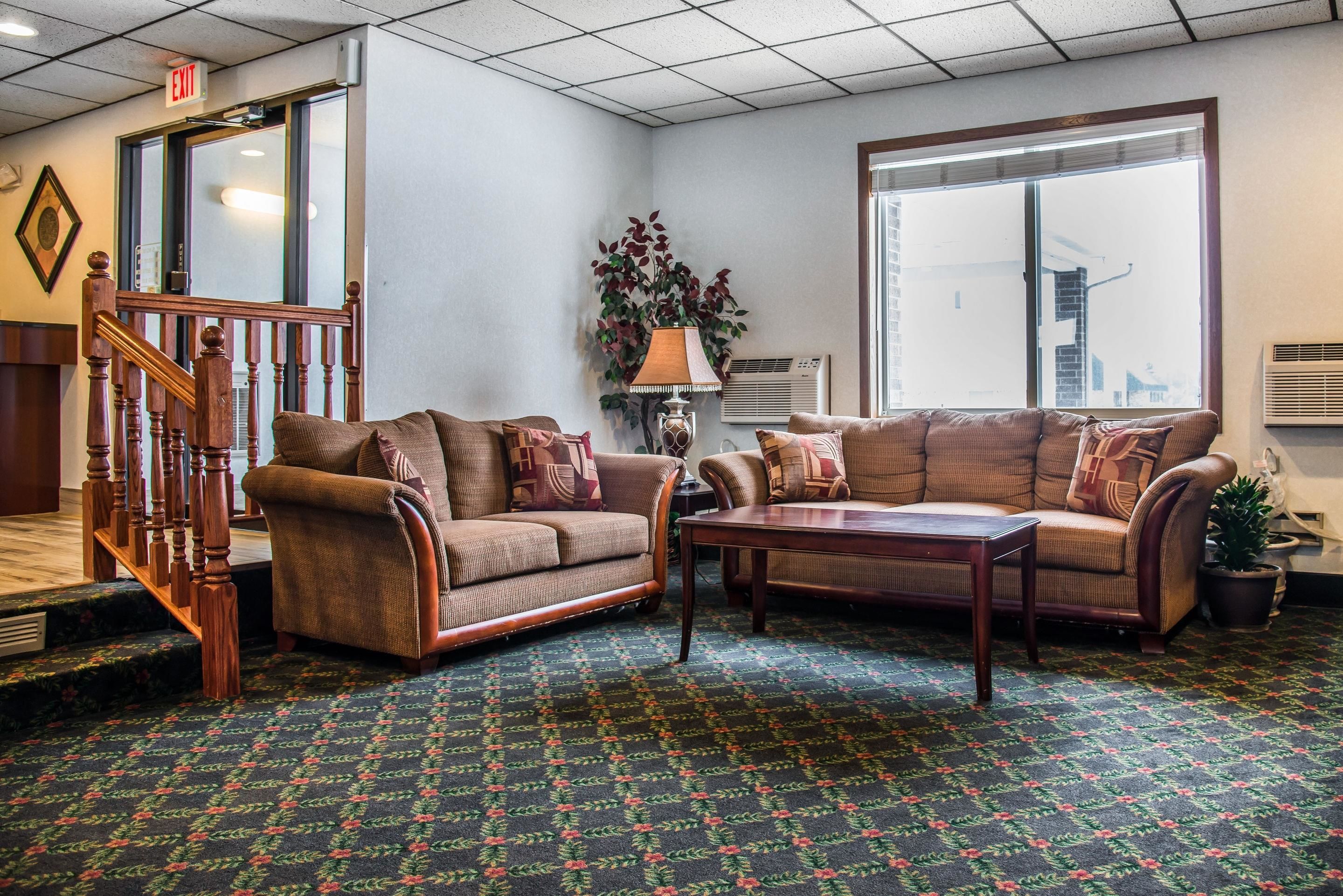 A hotel lobby with two sofas, a coffee table, a staircase, and a large window.