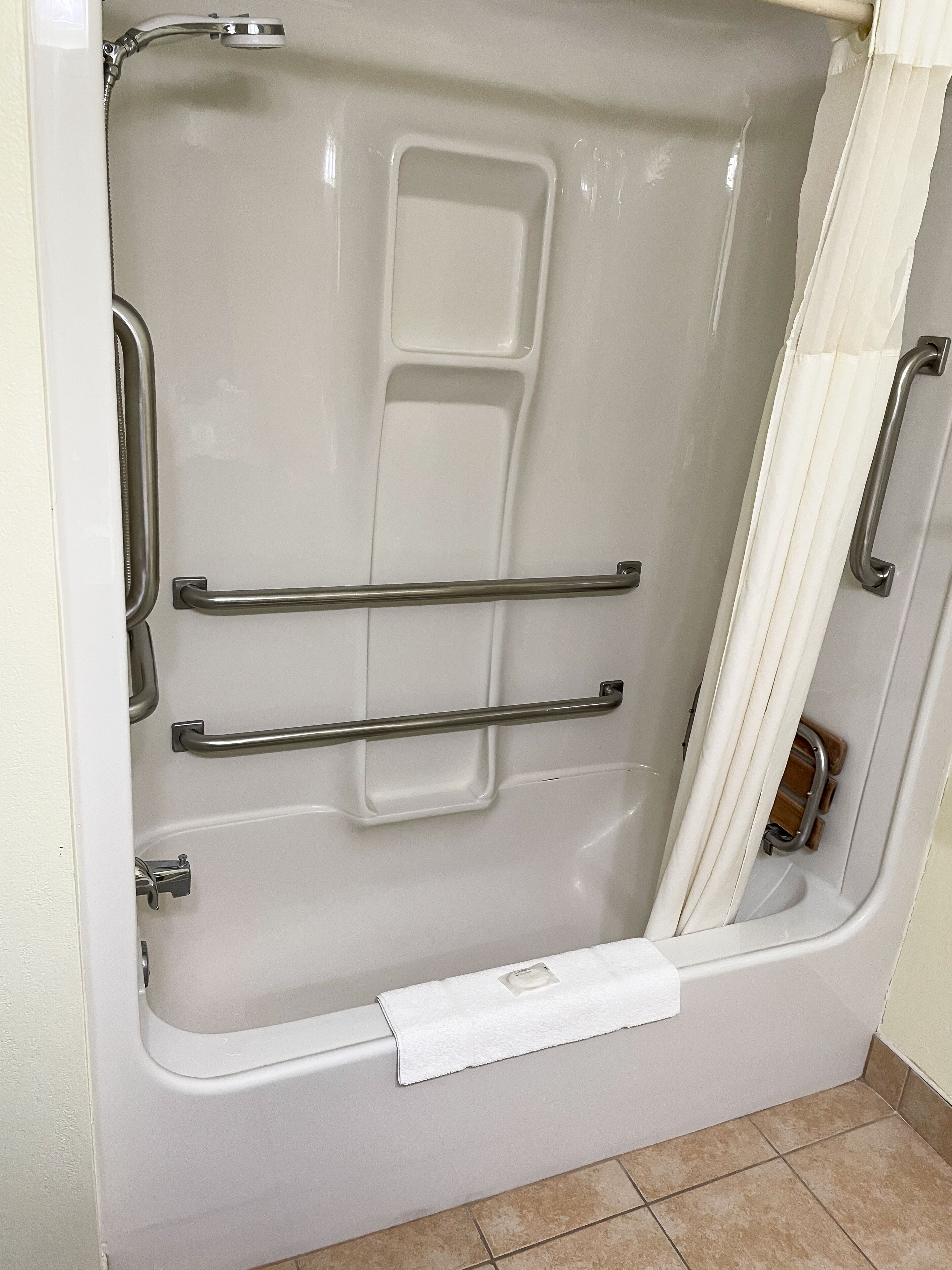 Una vasca da bagno con maniglie di sostegno e una tenda per la doccia.