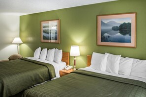 Habitación de hotel con dos camas, paredes verdes y cuadros de paisajes.
