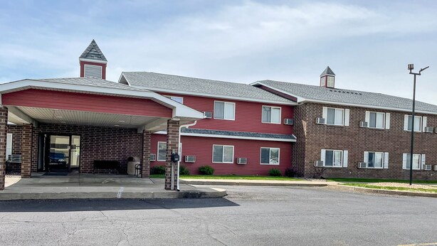A multi-story building with a red facade, a covered entrance, and a brick section.