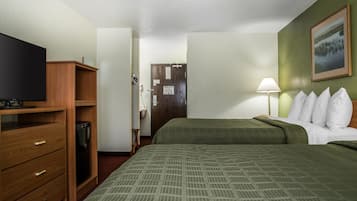 Una camera d'albergo con un letto, una televisione, una cassettiera in legno, una lampada e un quadro appeso al muro.