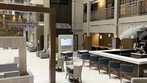 A spacious lobby with a bar area, seating arrangements, and a large screen. - Embassy Suites by Hilton Chicago Schaumburg Woodfield (Schaumburg)