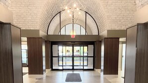 A spacious lobby with a high arched ceiling, a central chandelier, and a view through the glass doors. - Embassy Suites by Hilton Chicago Schaumburg Woodfield (Schaumburg)