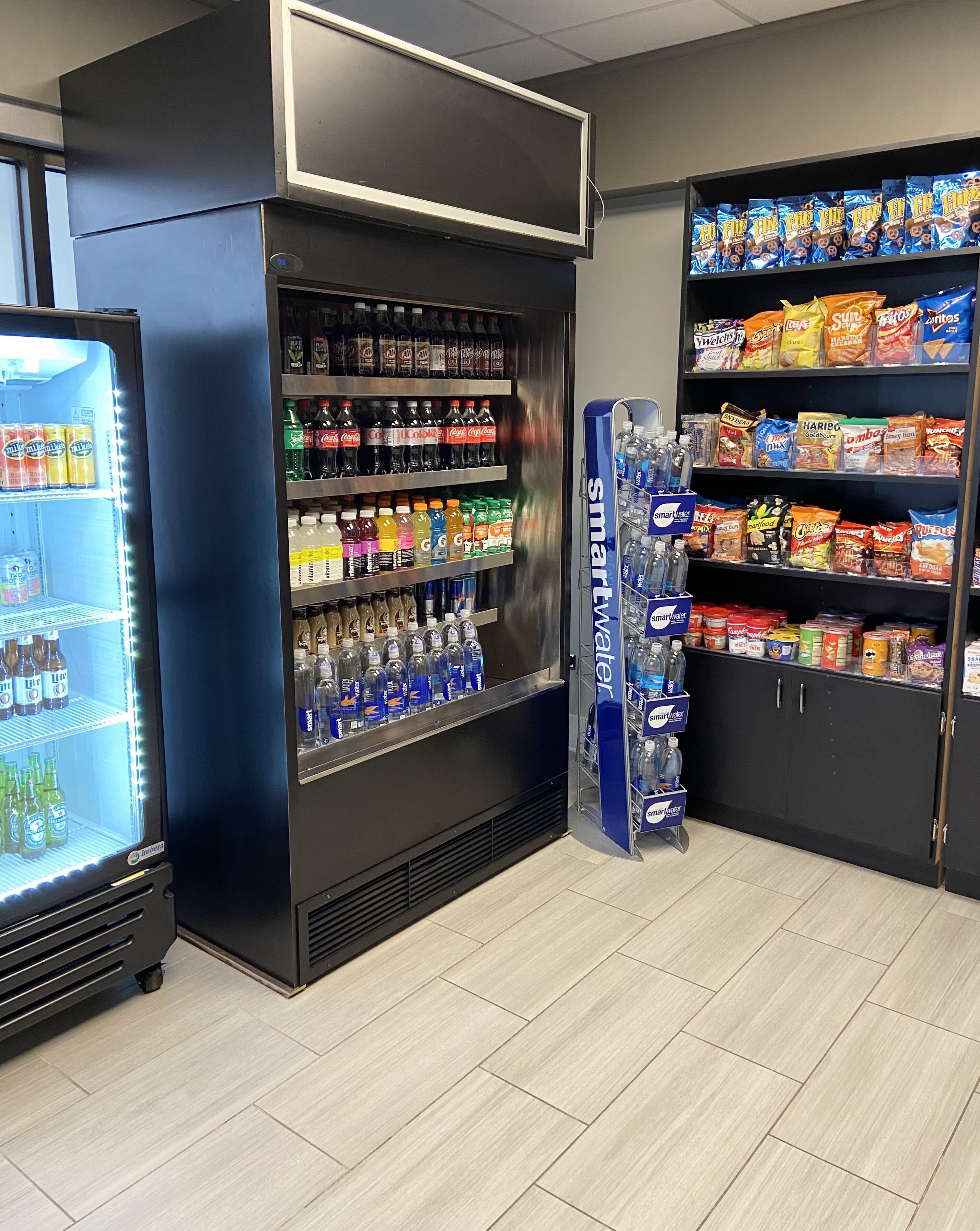 Ein Verkaufsbereich mit verschiedenen Getränken und Snacks, darunter ein Kühlbereich mit Wasserflaschen und ein Regal mit Chips und anderen Snacks.