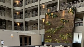 A spacious indoor dining area with multiple tables and chairs, a decorative wall with greenery, and a multi-level balcony with railings. - Embassy Suites by Hilton Chicago Schaumburg Woodfield (Schaumburg)