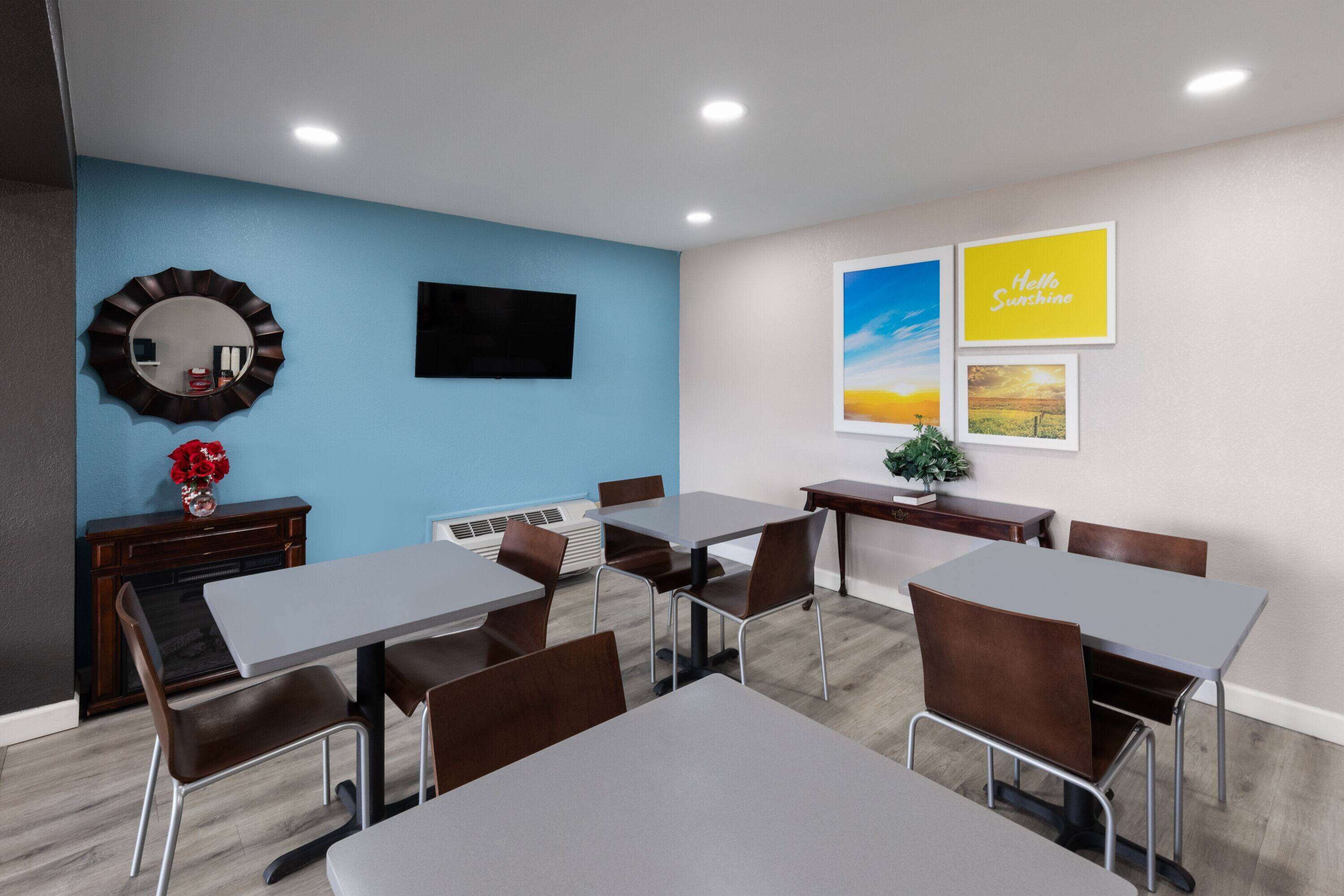 A conference room with tables and chairs, a fireplace, and framed pictures on the wall.