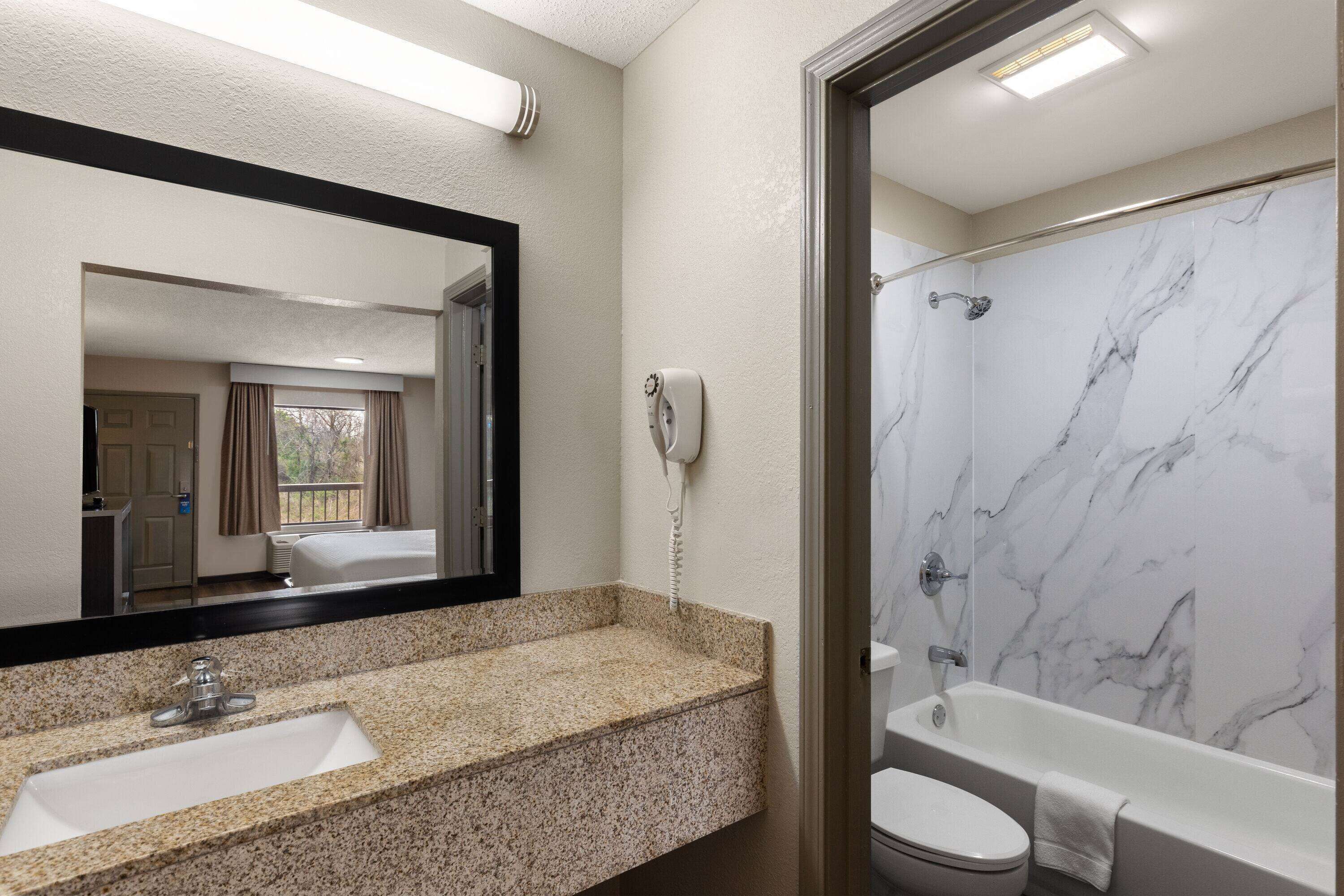 A bathroom with a marble shower, a sink, and a toilet.