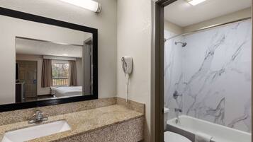 A bathroom with a marble shower, a sink, and a toilet.