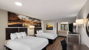 A hotel room with two beds, a desk, a TV, and artwork on the walls. - Days Inn by Wyndham Childersburg/Sylacauga (Childersburg)