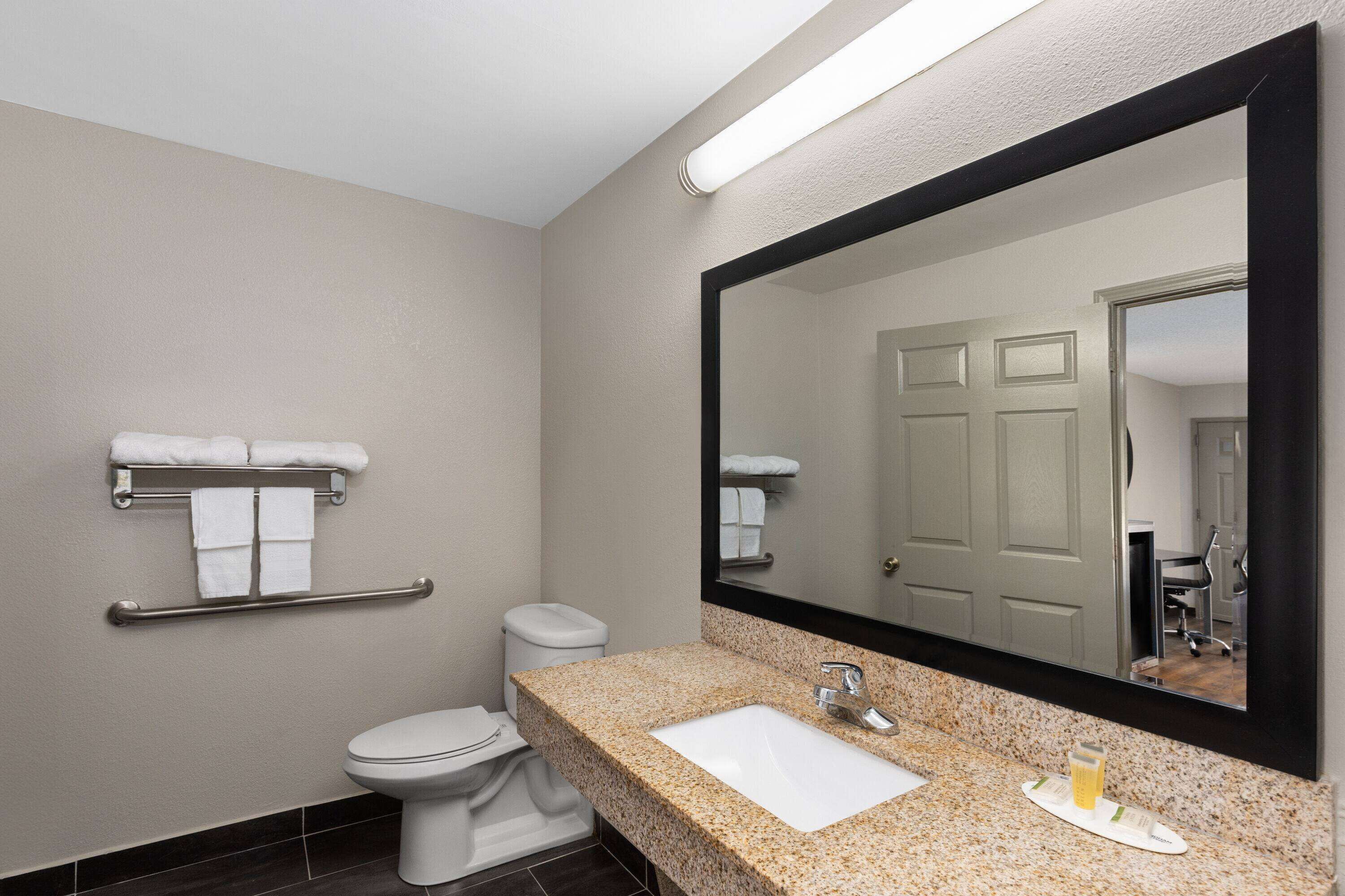 A bathroom with a toilet, a sink, a towel rack, and a mirror.