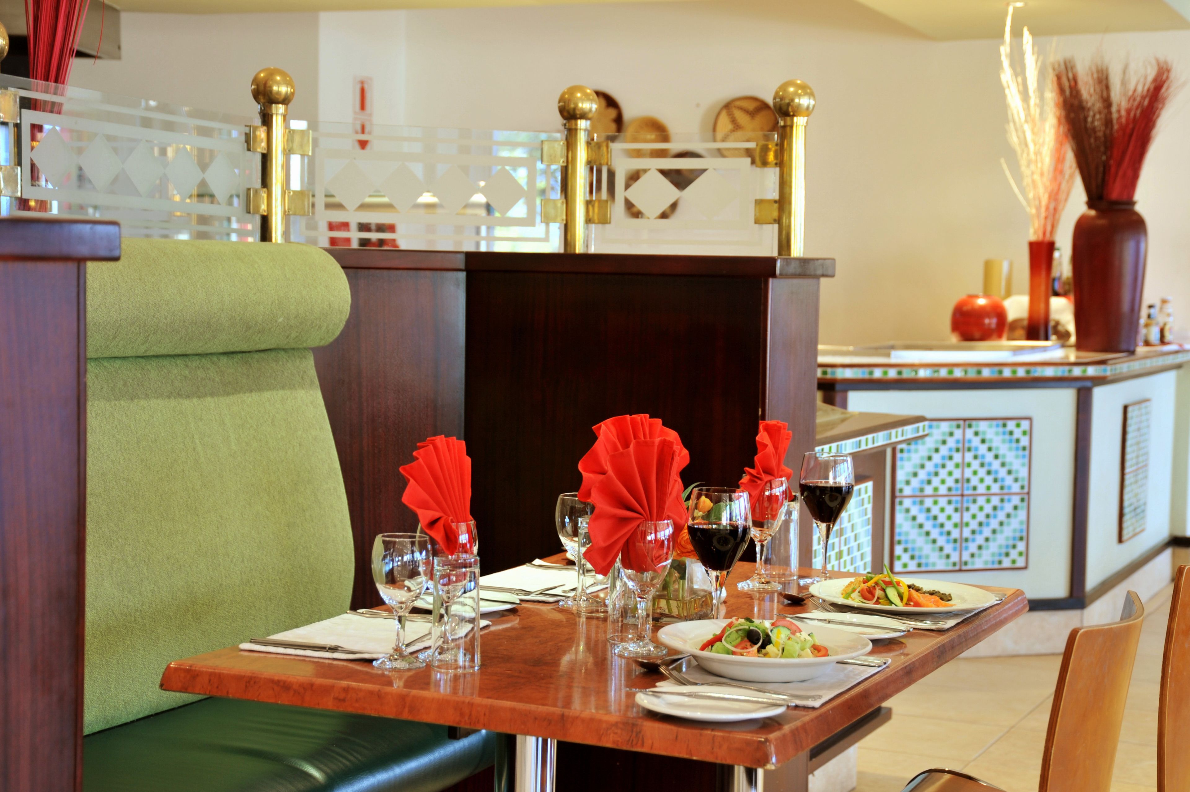 A dining table set with red napkins, wine glasses, and plates of food.