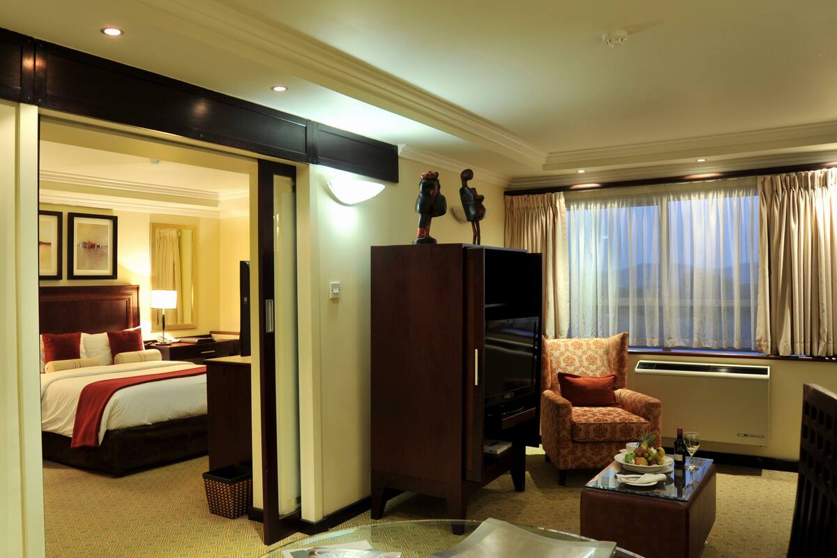 A hotel room with a bed, a desk, a chair, a TV, and a window with curtains.